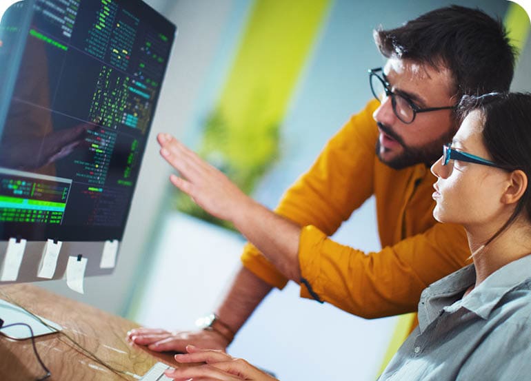 Closeup side view of couple of mid 20's software developers resolving some issues with the code they're currently working on. NOTE: code lines on the screen are imaginary and blurred.