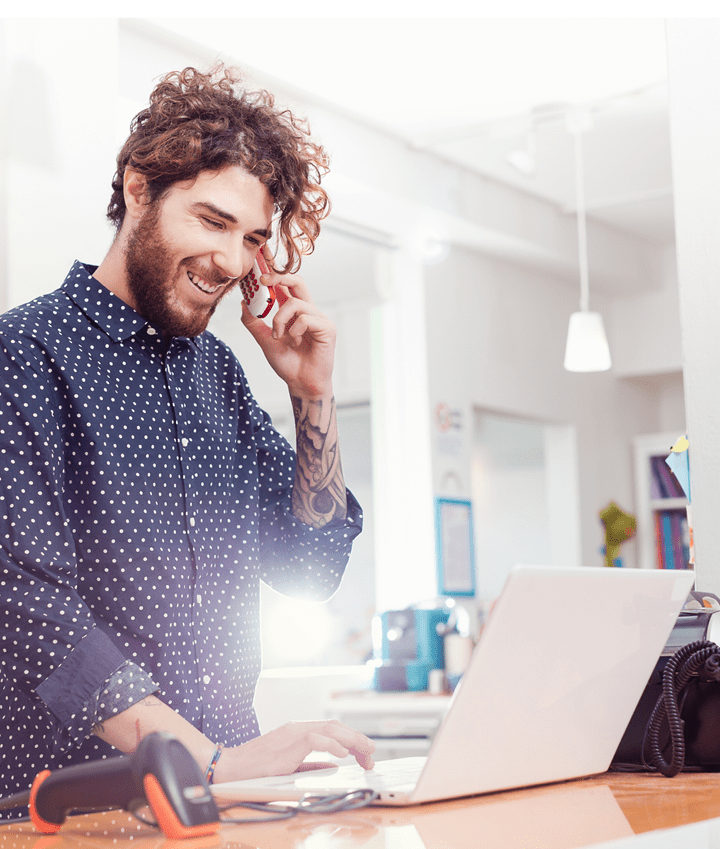 indoors, independent, shop, small business, working, standing, casual clothing, pois, shirt, beard, wireless technology, bookshop, books, curly hair, working, jeans, proud, smiling, toothy smile, laptop, computer barcode scanner, cash register, tattoos, holding, phone, mobile phone, typeing,