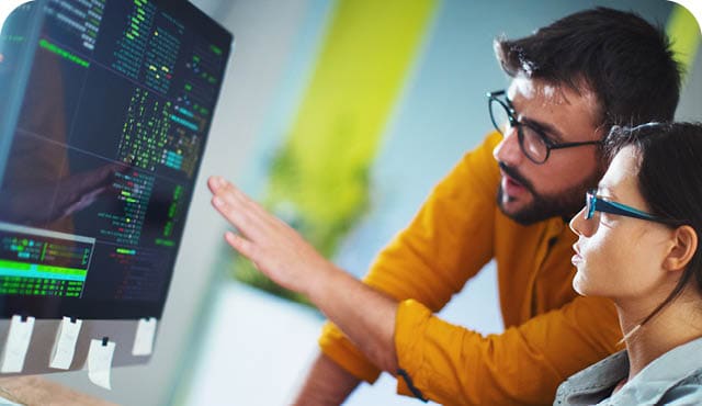 Closeup side view of couple of mid 20's software developers resolving some issues with the code they're currently working on. NOTE: code lines on the screen are imaginary and blurred.